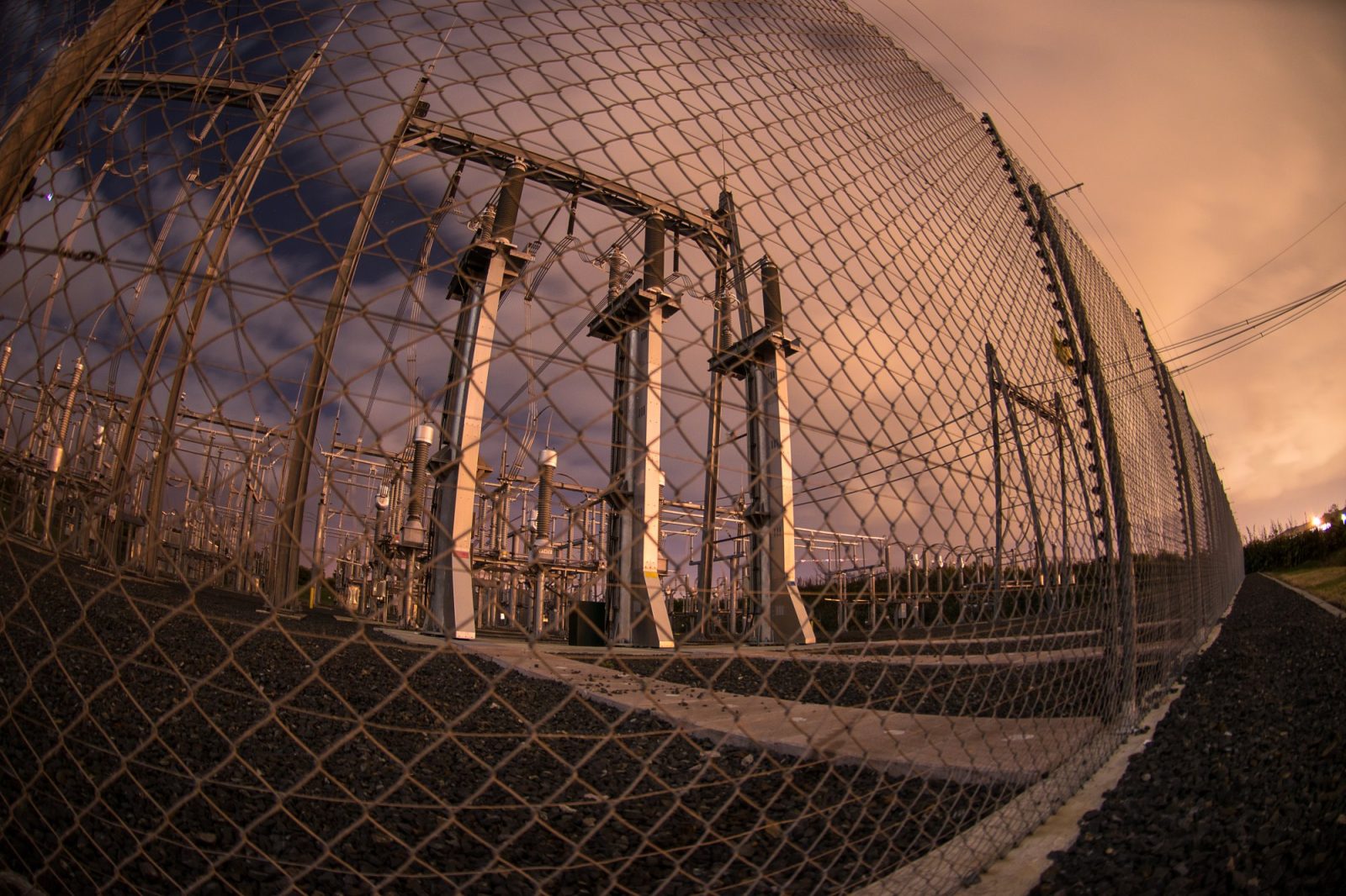 A fence with barbed wire surrounds a substation