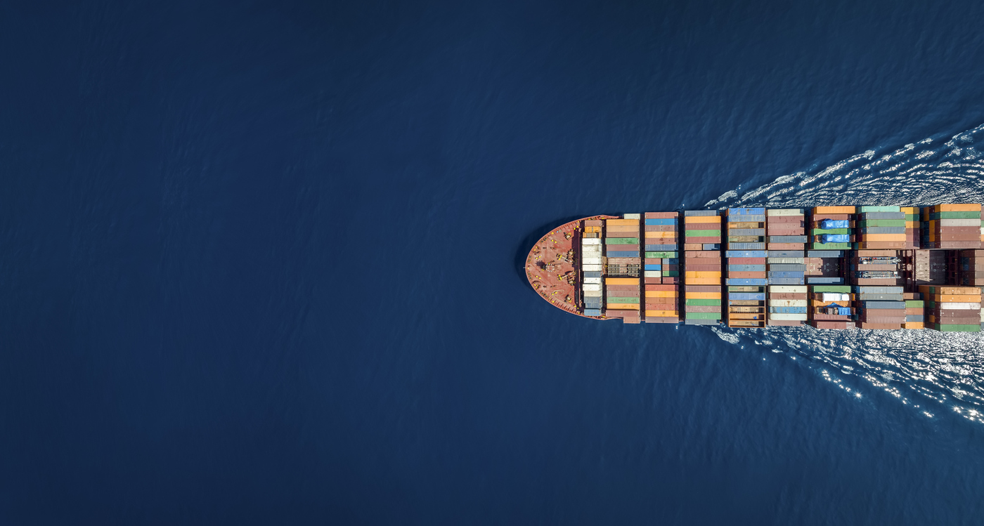 Aerial top down view of a large container cargo ship in motion over open ocean 