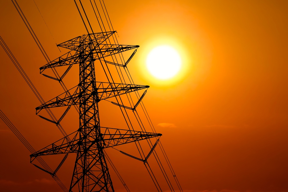 Summer sun glows through haze behind transmission lines